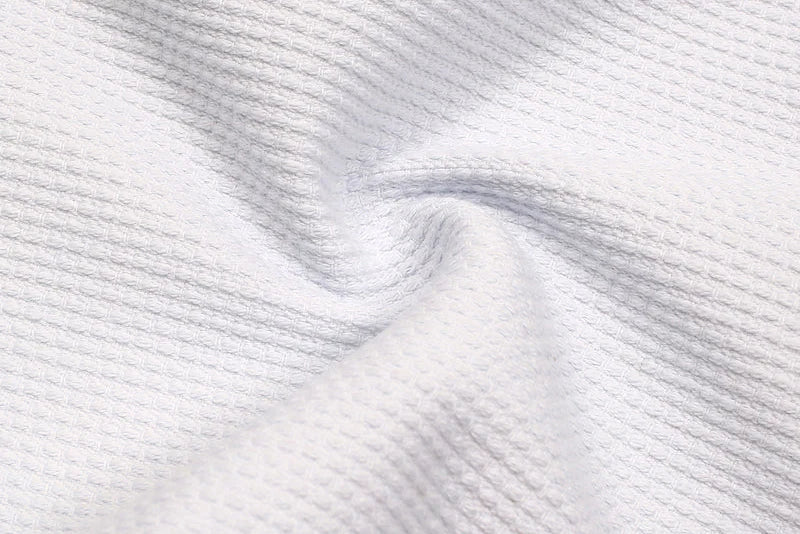 BJJ Gi Weaves Explained: From Traditional Weaves to Modern Pearl Weave close-up of white woven fabric texture.
