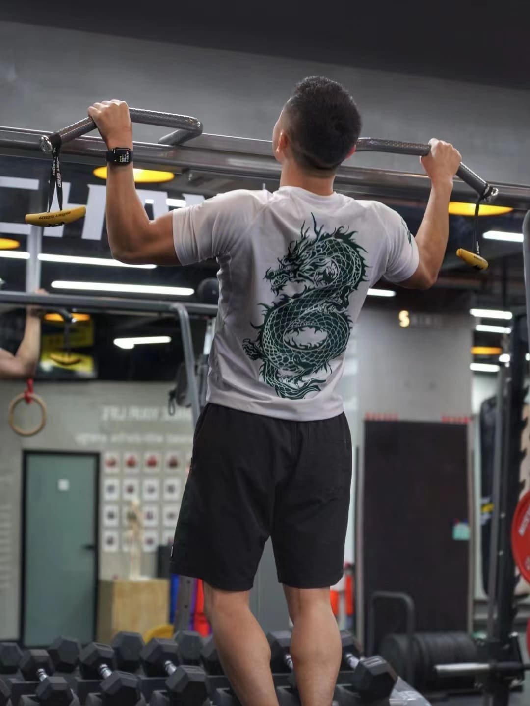 Man wearing Dragon Year Limited Edition Rash Guard performs pull-up in gym.