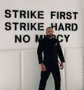 Homem vestindo o kimono de Jiu-Jitsu brasileiro BLITZ Sun & Moon em pé contra uma parede com mensagens motivacionais.