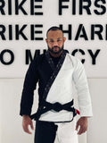 Man wearing BLITZ Sun & Moon Brazilian Jiu-Jitsu Gi, combining durability and style, against motivational wall.