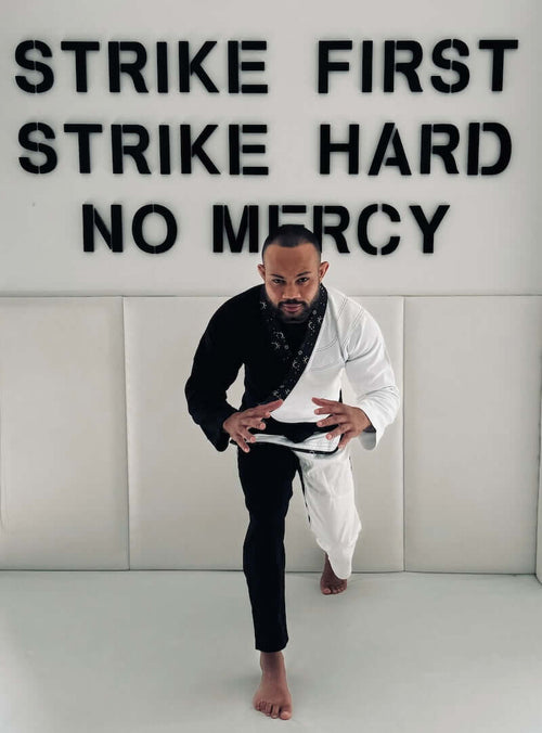 A practitioner wearing the BLITZ Sun & Moon Brazilian Jiu-Jitsu Gi striking a pose in front of motivational text.