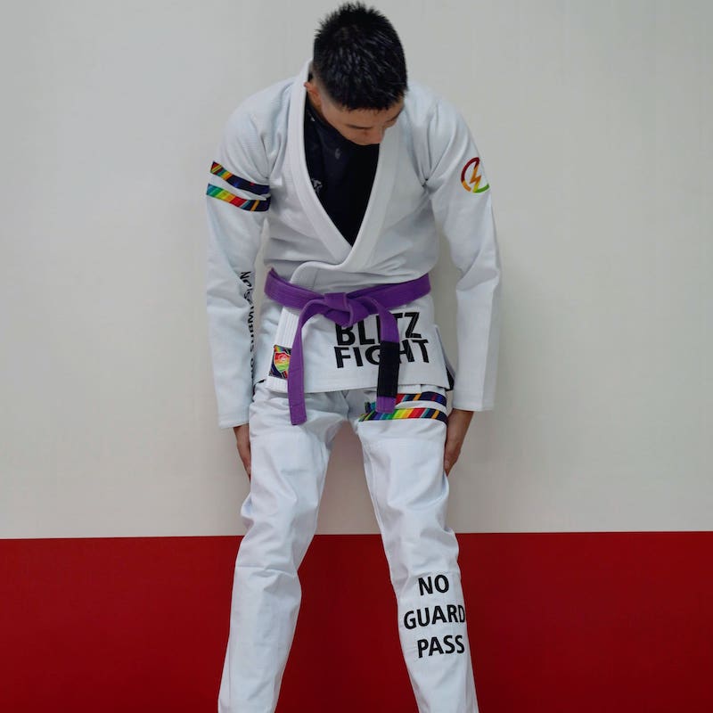 Model in a white rainbow pattern BJJ gi looking down