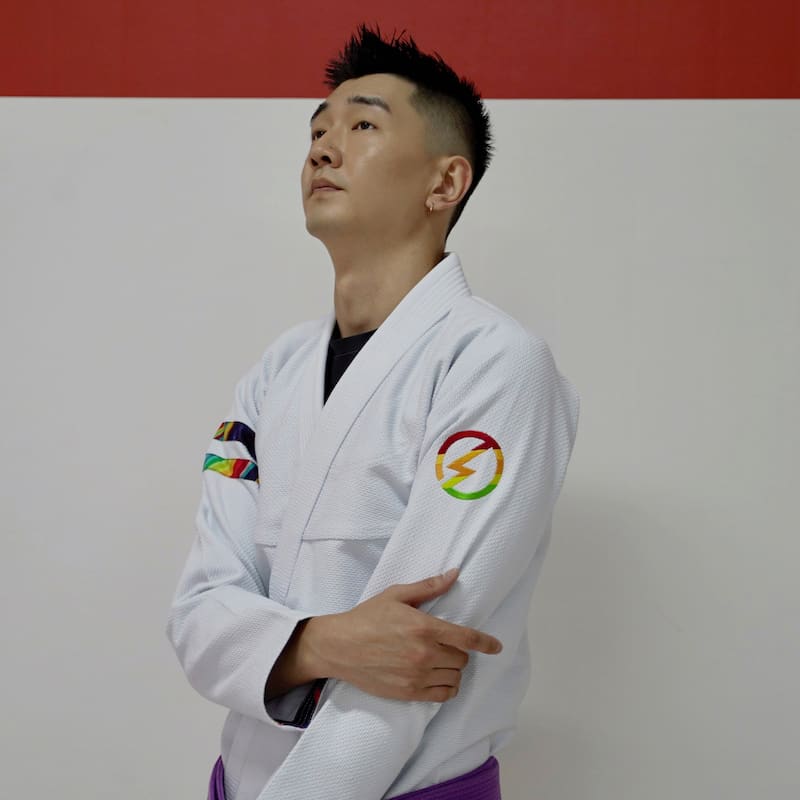 Side view of a model wearing a white rainbow pattern Brazilian Jiu-Jitsu gi