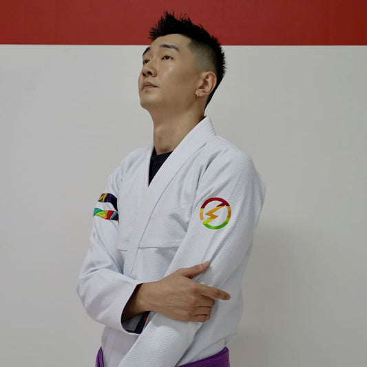 Side view of a model wearing a white rainbow pattern Brazilian Jiu-Jitsu gi